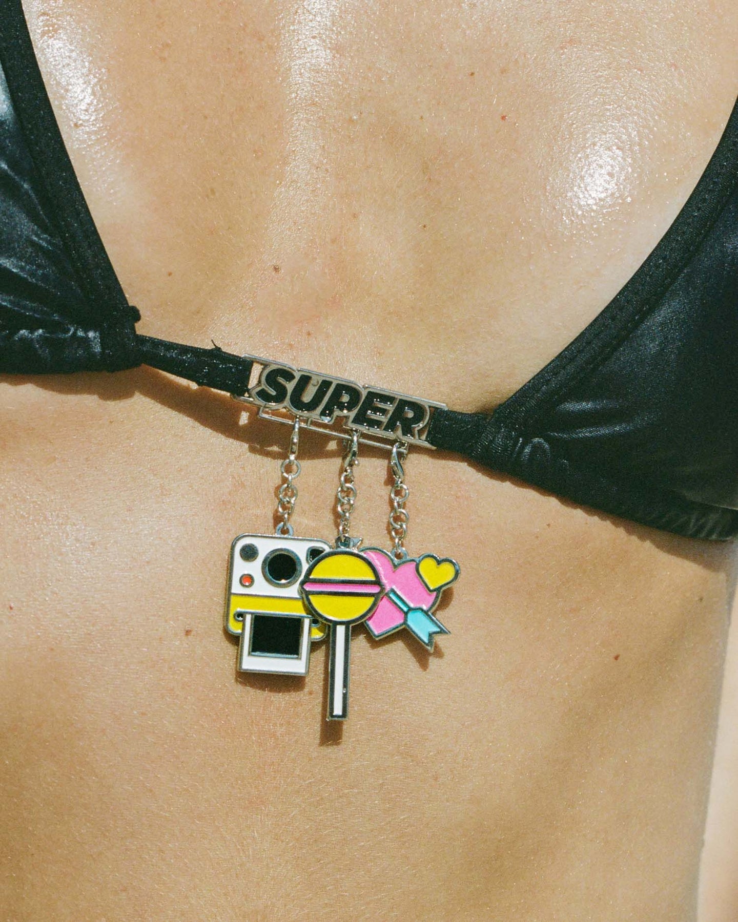 Black triangle bikini with customizable charm bar, featuring vibrant charms, perfect for beach activities and tanning.