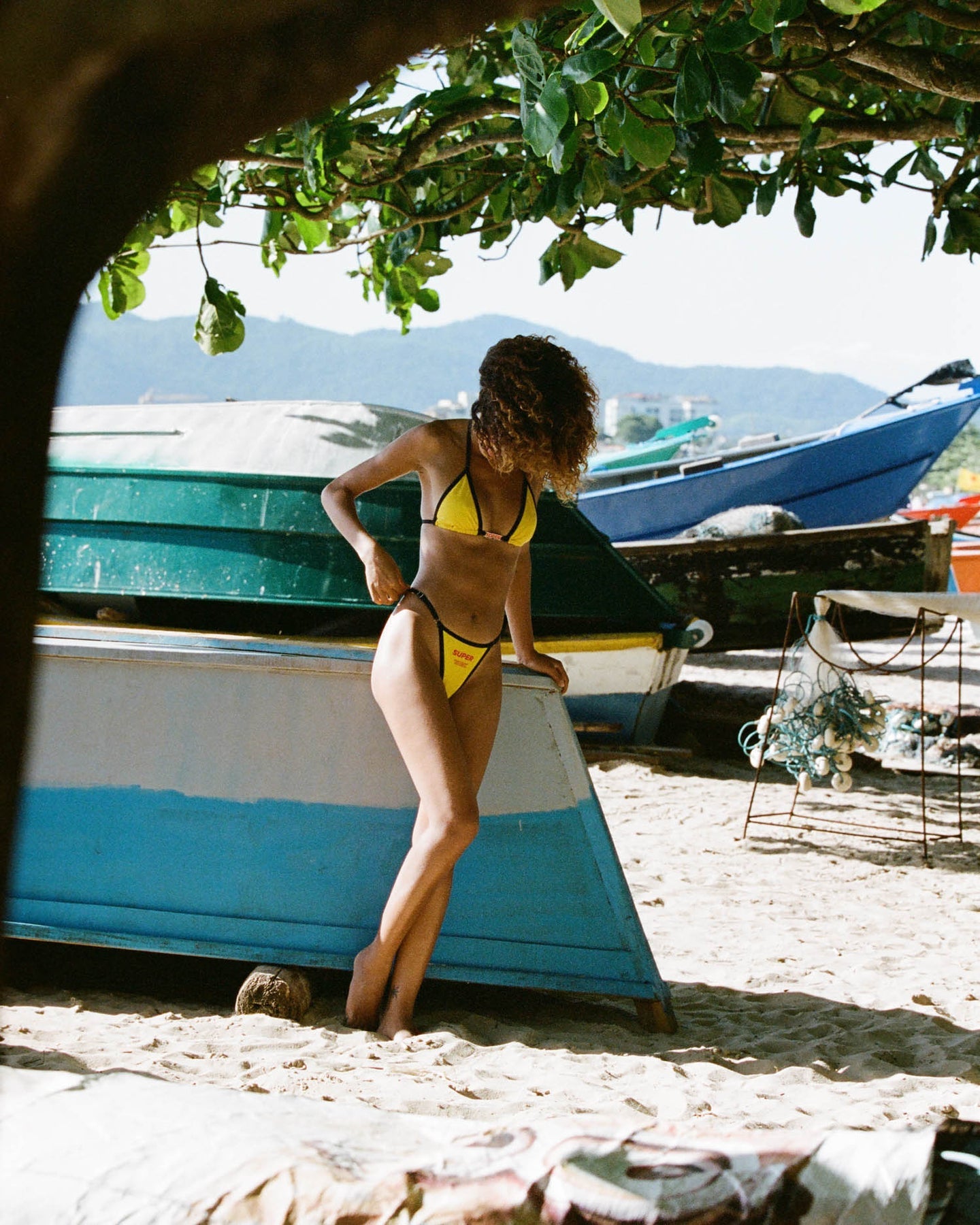A model radiates sophistication in a mid-rise triangle-style yellow bikini adorned with a sleek black outline on the top. With its timeless design and adjustable sides, this swimwear captures a chic and classic essence for a standout summer bikini look.