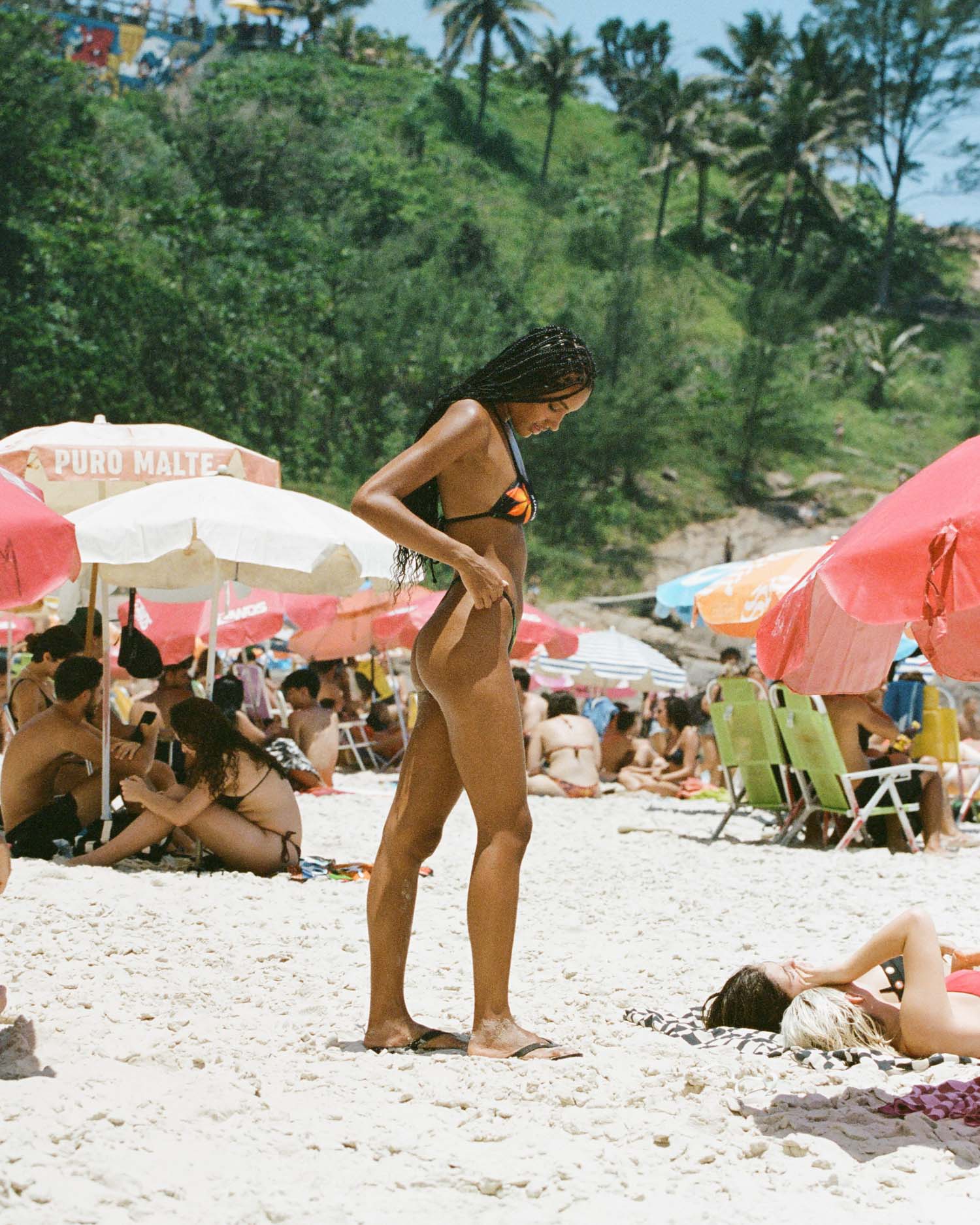 Stepping into elegance, the model showcases women's thong-style bikini in sleek black with a flattering halter neck. The adjustable side and high-waisted cut create a stylish and comfortable beach look.