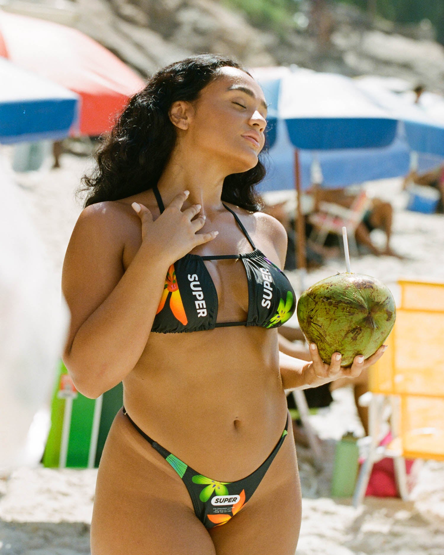 Stepping into elegance, the model showcases women's thong-style bikini in sleek black with a flattering halter neck. The adjustable side and high-waisted cut create a stylish and comfortable beach look.