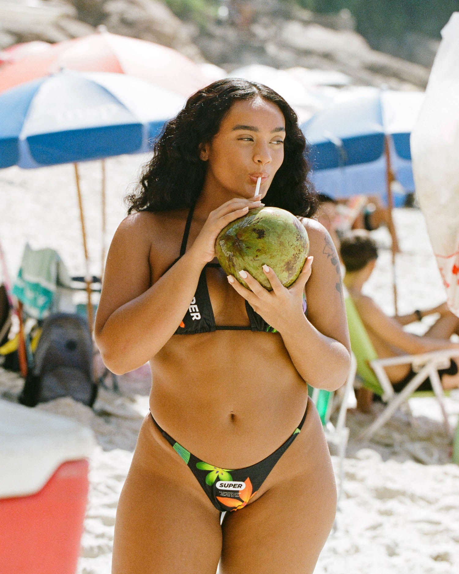 Stepping into elegance, the model showcases women's thong-style bikini in sleek black with a flattering halter neck. The adjustable side and high-waisted cut create a stylish and comfortable beach look.