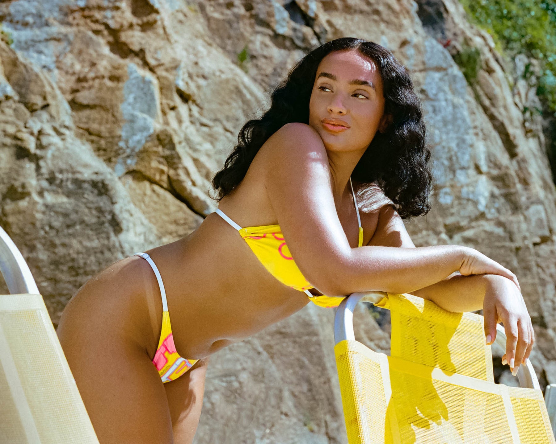 In vibrant nitro yellow, a model dons a bikini featuring the classic SUPER logo. The high-waisted thong design, combined with adjustable sides, makes this swimwear a bold and chic choice for a standout summer bikini look.