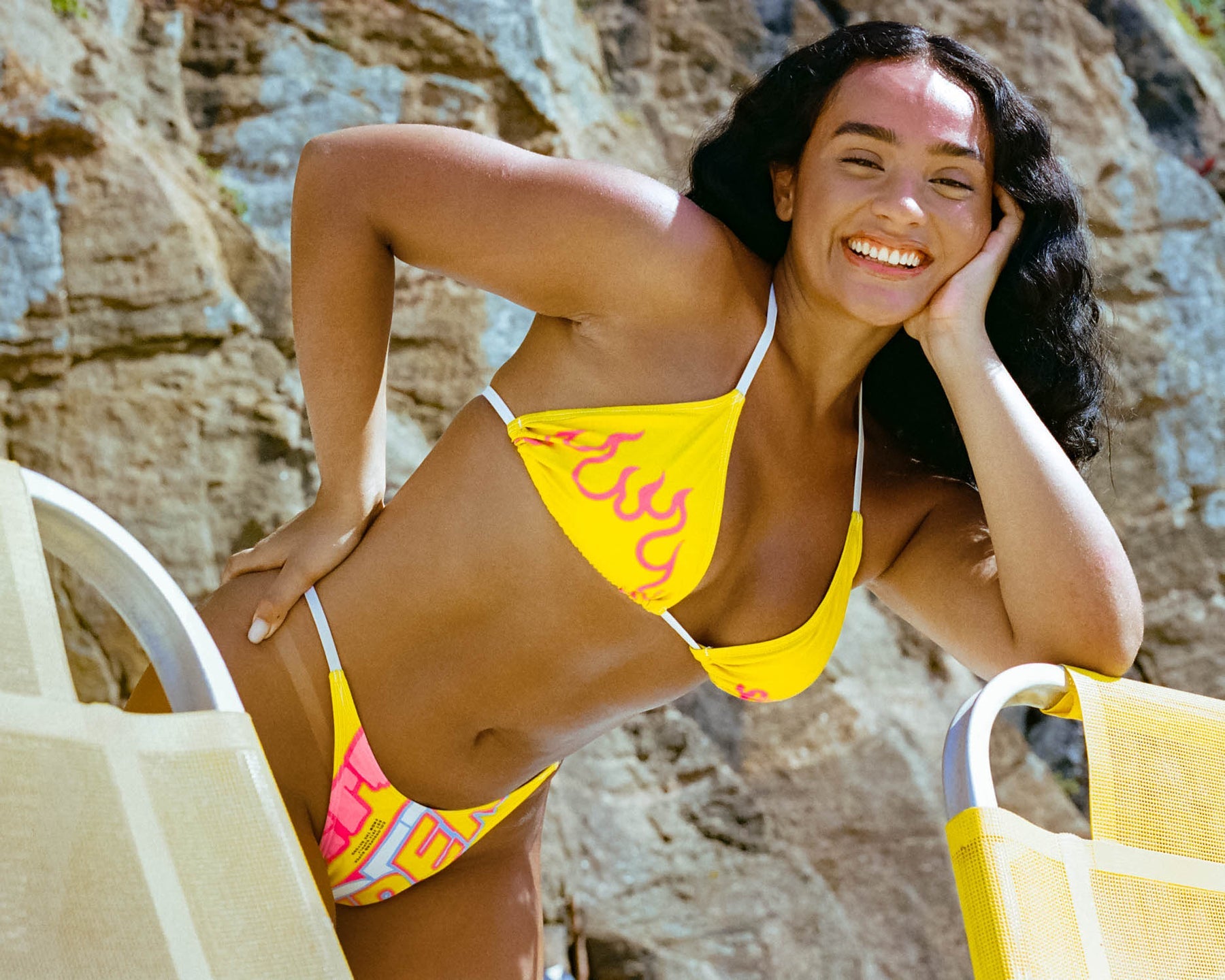 In vibrant nitro yellow, a model dons a bikini featuring the classic SUPER logo. The high-waisted thong design, combined with adjustable sides, makes this swimwear a bold and chic choice for a standout summer bikini look.