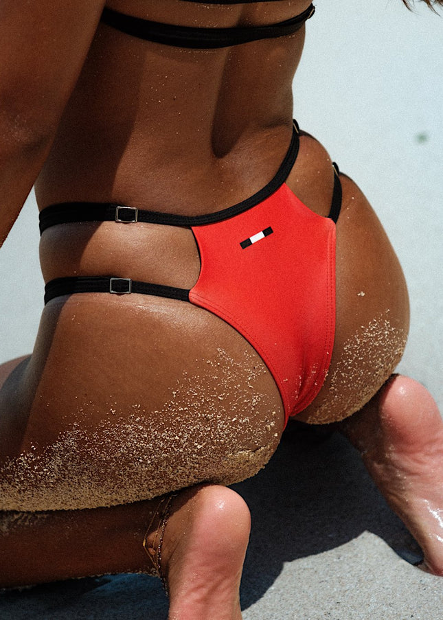 Super close up rear shot featuring the model in red bikini bottoms with high wasted and adjustable sides, highlighting the intricate details for a stylish and customizable fit.