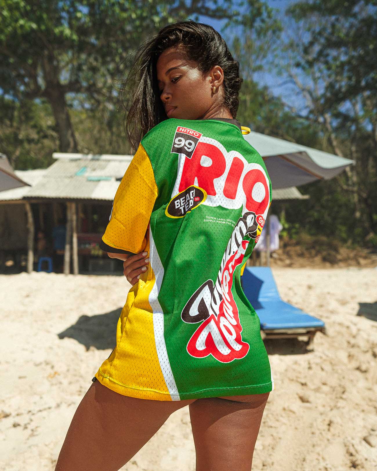 Model wearing oversized Ipanema jersey at the beach, showcasing vibrant colors and mesh fabric for summer style.