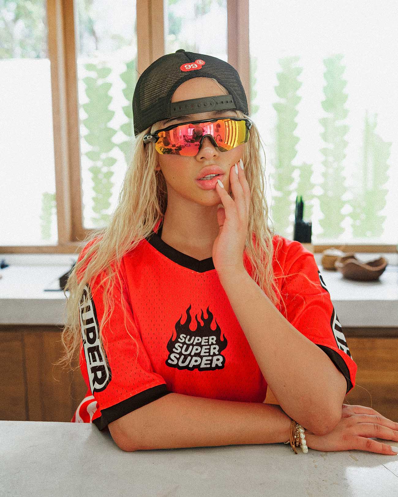 Model wearing oversized red Heat jersey with cooling perforations, paired with stylish glasses and cap, perfect for summer activities.